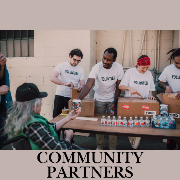 Group of diverse individuals with volunteer shirts on serving food to someone unhoused. Text reads "Community Partners".